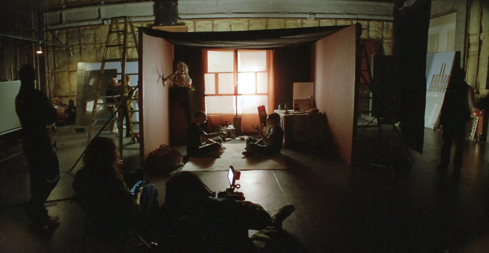 Inside the sound stage with a fake room set up and reddish-brown lighting