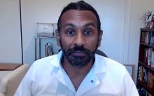 Mayuran Tiruchelvam speaks into a webcam while sitting in a home office