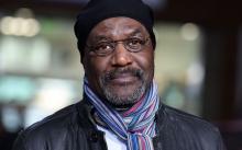 Delroy Lindo wearing a jacket, scarf and hat