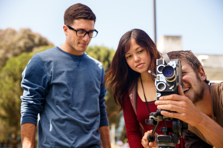 Three students looking through camera