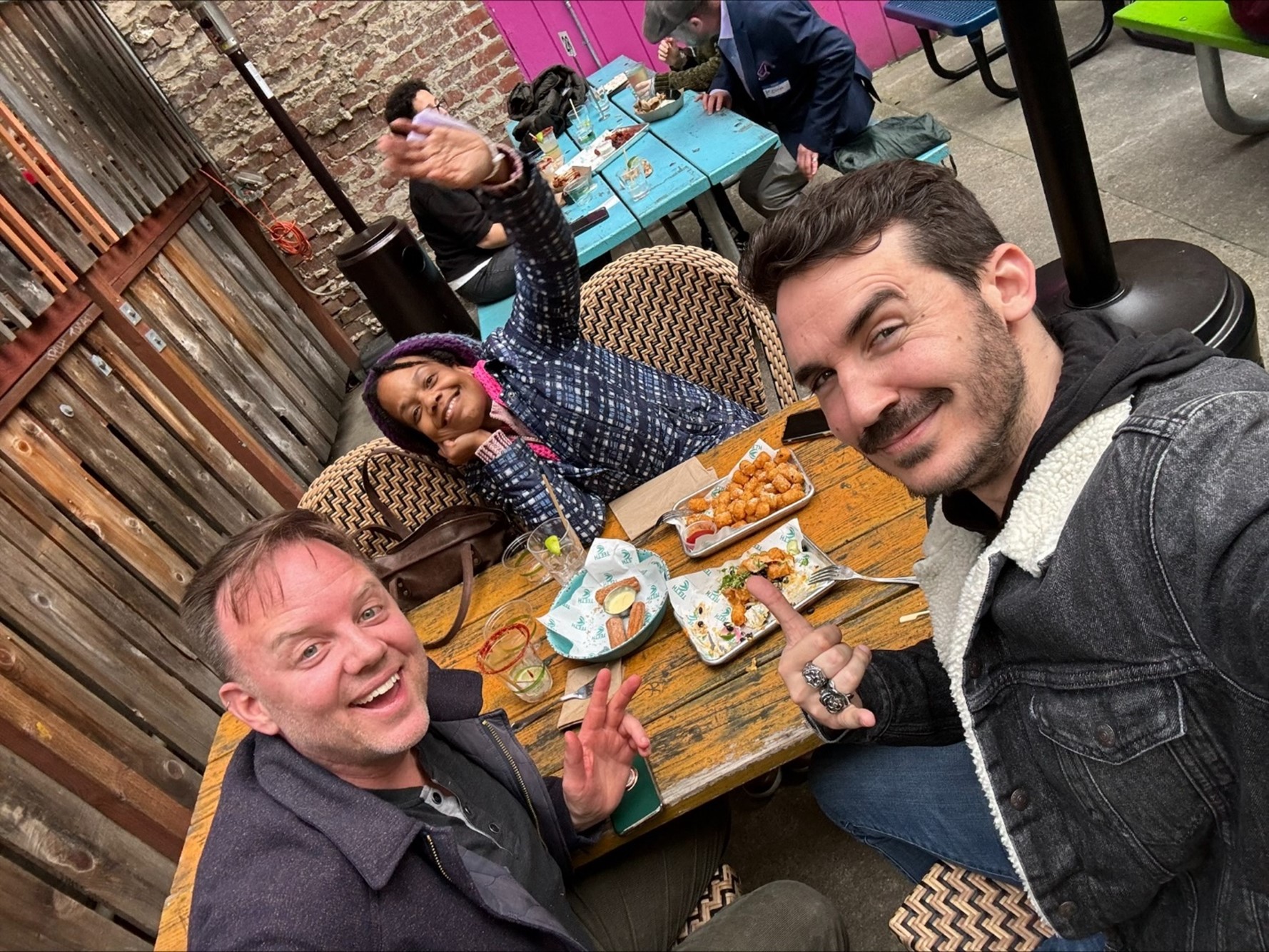 Three people around a table of snacks smiling into the camera