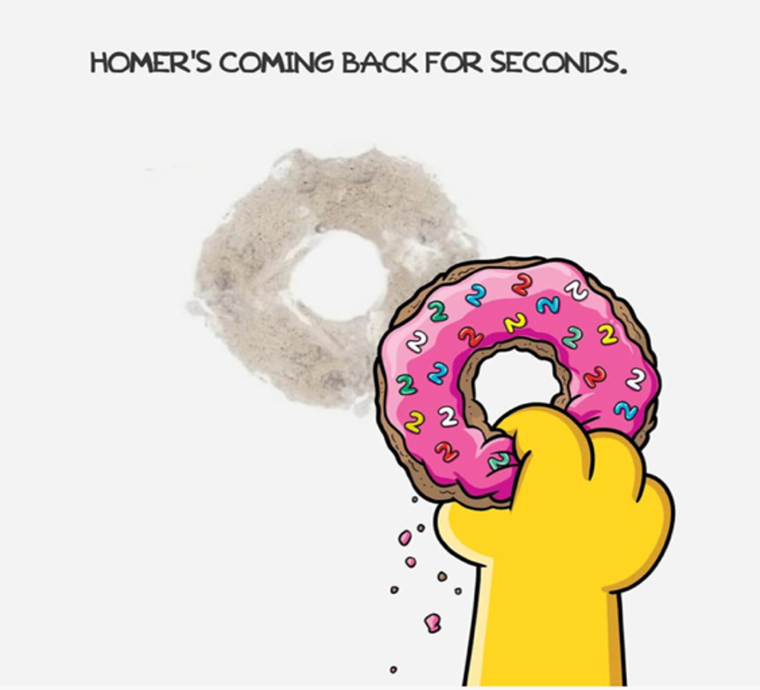 Closeup of Homer's hand holding a pink donut with the number 2 as sprinkles